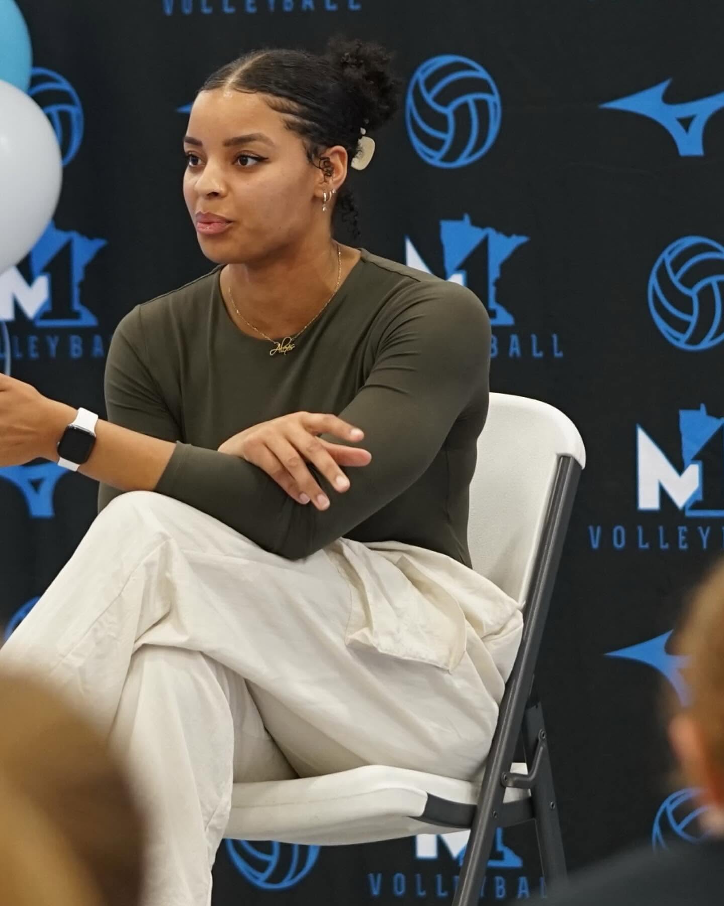 Alexis Hart speaking on a panel in front of an M1 Volleyball backdrop