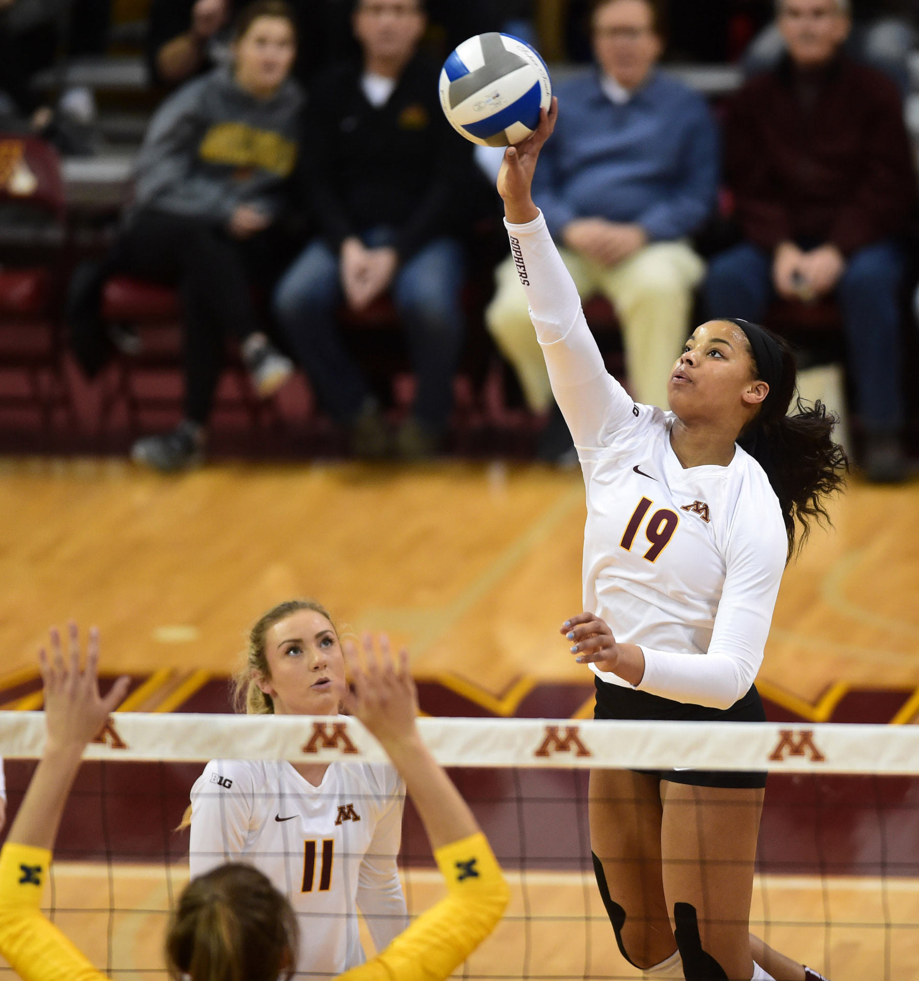 Alexis Lexi Hart attacking the volleyball above the net for the University of Minnesota